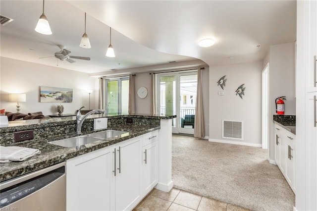 kitchen with sink, hanging light fixtures, stainless steel dishwasher, light colored carpet, and white cabinetry