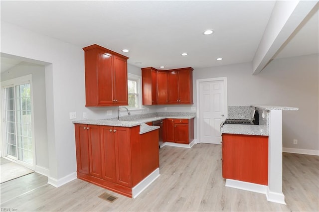 kitchen with plenty of natural light, light hardwood / wood-style floors, and light stone countertops