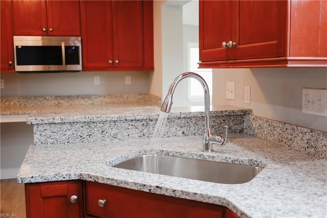 kitchen with light stone counters, sink, and hardwood / wood-style floors