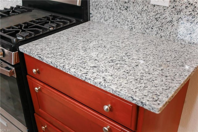 details featuring decorative backsplash, light stone counters, and high end stainless steel range