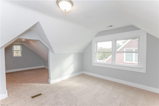 bonus room with light colored carpet and vaulted ceiling