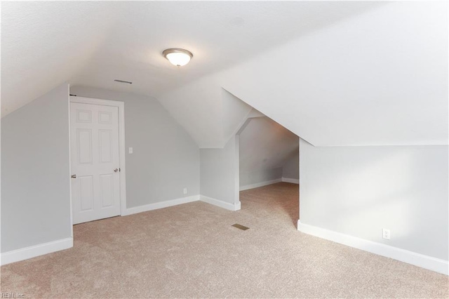 additional living space with light colored carpet and vaulted ceiling