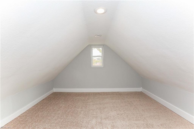 bonus room featuring a textured ceiling, light colored carpet, and vaulted ceiling