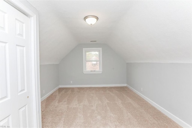 additional living space with light colored carpet and vaulted ceiling