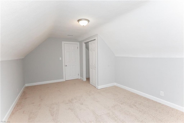 additional living space featuring light colored carpet and lofted ceiling