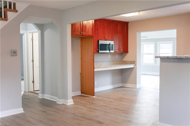 kitchen with built in desk and light hardwood / wood-style flooring