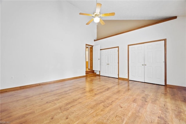 unfurnished bedroom with two closets, light hardwood / wood-style floors, high vaulted ceiling, and ceiling fan