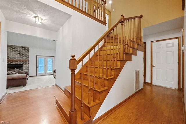 stairway with a fireplace, wood-type flooring, and a textured ceiling