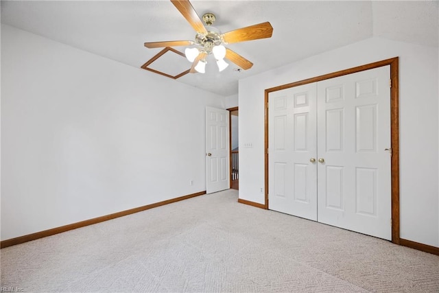 unfurnished bedroom featuring lofted ceiling, a closet, ceiling fan, and light colored carpet