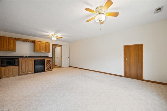 unfurnished living room featuring light carpet and ceiling fan