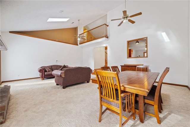 carpeted dining room featuring a skylight, ceiling fan, and high vaulted ceiling