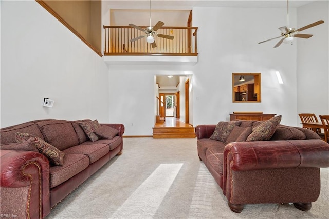 living room with ceiling fan, light colored carpet, and a towering ceiling