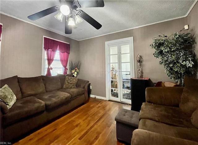 living room featuring ceiling fan, wood-type flooring, a textured ceiling, and ornamental molding