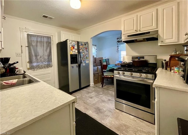 kitchen featuring white cabinets, light hardwood / wood-style flooring, ornamental molding, a textured ceiling, and stainless steel appliances