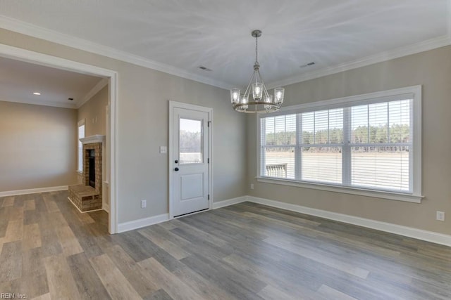 interior space with a fireplace, crown molding, hardwood / wood-style floors, and an inviting chandelier