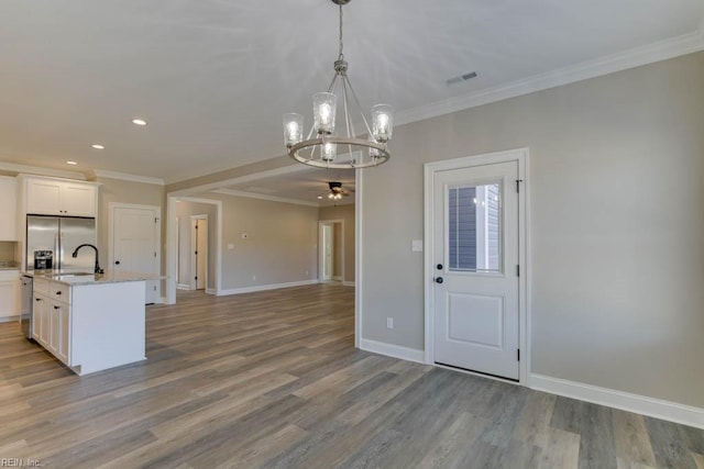 kitchen with stainless steel fridge with ice dispenser, ceiling fan with notable chandelier, wood-type flooring, and an island with sink