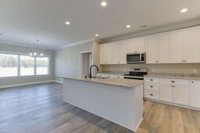 kitchen featuring white cabinetry, sink, hanging light fixtures, stainless steel appliances, and a kitchen island with sink