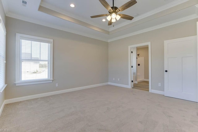 empty room featuring ceiling fan, a raised ceiling, ornamental molding, and light carpet