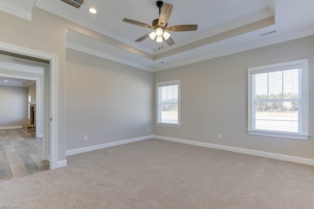 carpeted spare room featuring ceiling fan, a healthy amount of sunlight, ornamental molding, and a fireplace