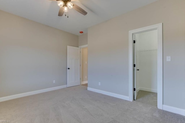 unfurnished bedroom with ceiling fan, a closet, light colored carpet, and a spacious closet