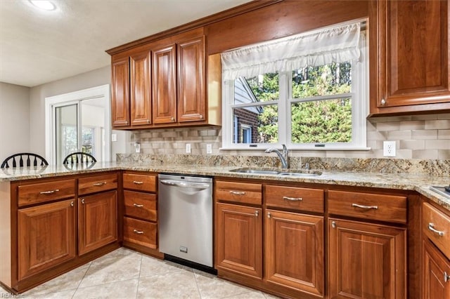 kitchen with dishwasher, a wealth of natural light, light stone countertops, and sink