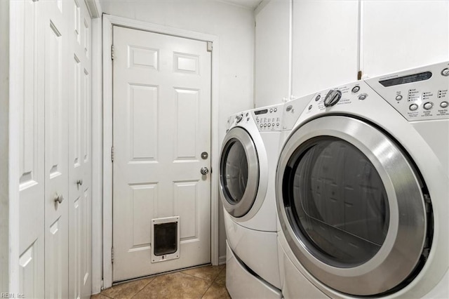 clothes washing area with washer and clothes dryer, light tile patterned floors, and cabinets