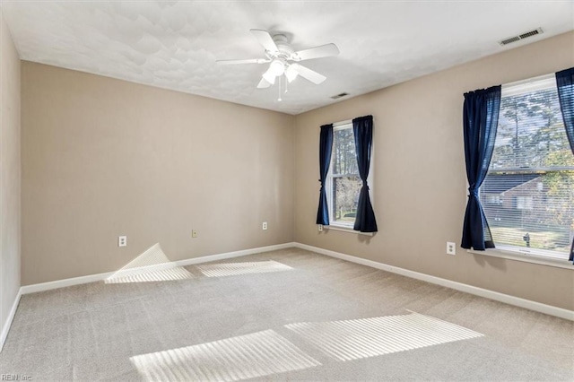 empty room with ceiling fan, a healthy amount of sunlight, and light colored carpet