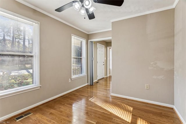 spare room featuring a wealth of natural light, ceiling fan, ornamental molding, and hardwood / wood-style flooring