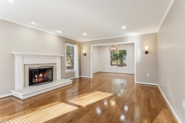 unfurnished living room with a fireplace, wood-type flooring, plenty of natural light, and ornamental molding