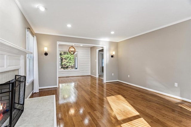 unfurnished living room featuring hardwood / wood-style flooring, a notable chandelier, crown molding, and a brick fireplace