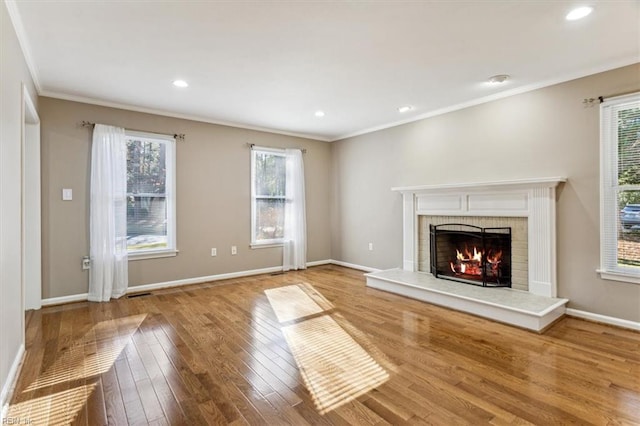 unfurnished living room featuring a brick fireplace, a wealth of natural light, and hardwood / wood-style flooring