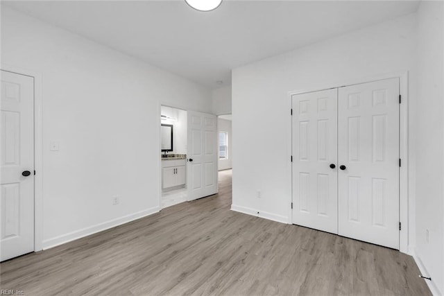 unfurnished bedroom featuring ensuite bathroom, sink, and light wood-type flooring