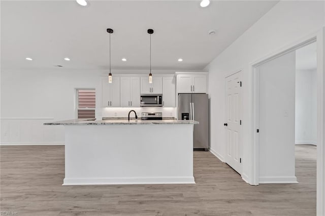 kitchen with white cabinetry, light stone counters, pendant lighting, a kitchen island with sink, and appliances with stainless steel finishes