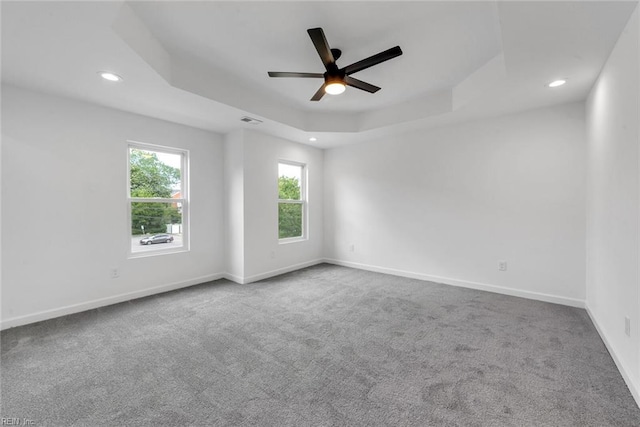 spare room featuring carpet, a raised ceiling, and ceiling fan