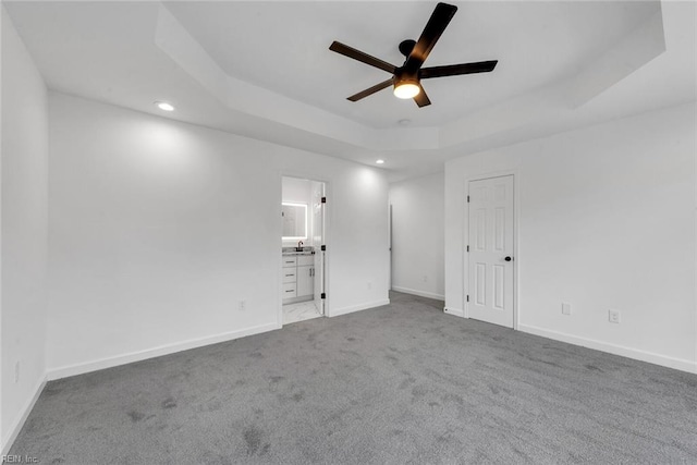 carpeted empty room featuring a tray ceiling and ceiling fan