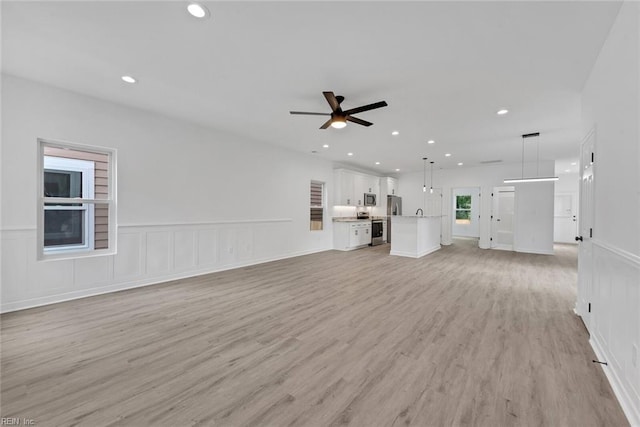 unfurnished living room featuring ceiling fan and light hardwood / wood-style flooring