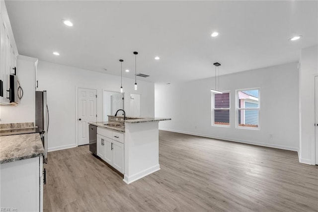 kitchen featuring pendant lighting, light hardwood / wood-style floors, white cabinetry, and a kitchen island with sink