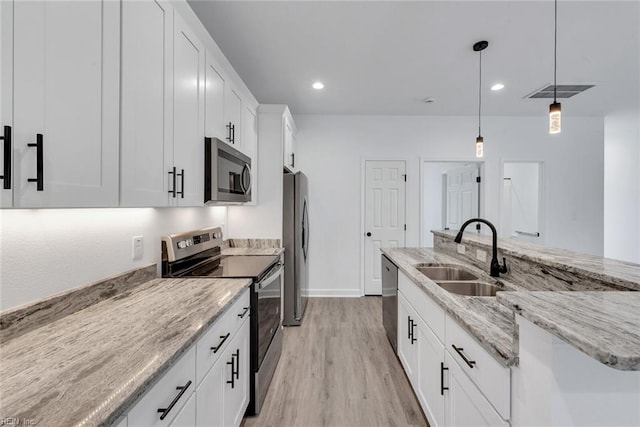 kitchen featuring sink, light hardwood / wood-style flooring, decorative light fixtures, white cabinetry, and stainless steel appliances