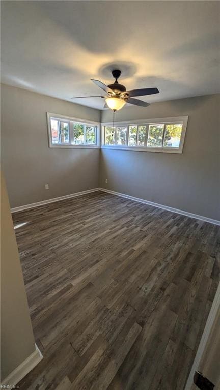 empty room featuring plenty of natural light, ceiling fan, and dark hardwood / wood-style flooring