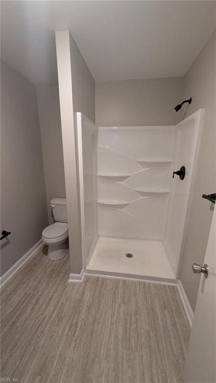 bathroom with a shower, toilet, and hardwood / wood-style flooring