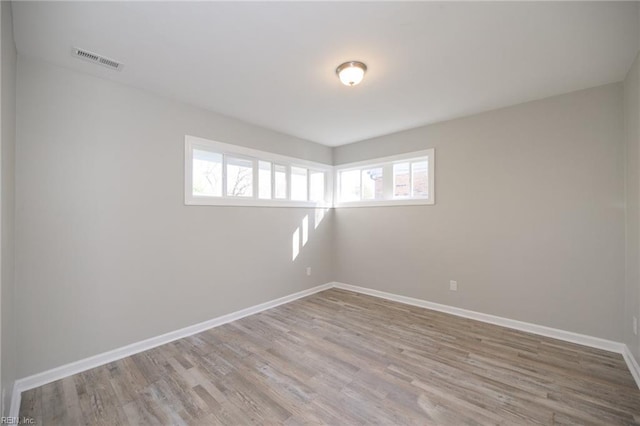 empty room with plenty of natural light and hardwood / wood-style flooring