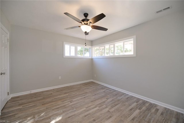 empty room with hardwood / wood-style floors, ceiling fan, and a healthy amount of sunlight