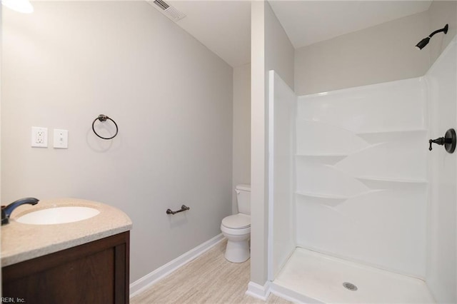 bathroom featuring a shower, wood-type flooring, vanity, and toilet