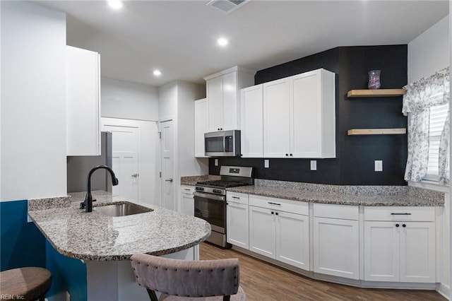 kitchen featuring white cabinetry, sink, wood-type flooring, and appliances with stainless steel finishes