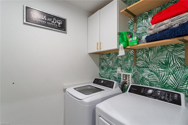 clothes washing area with cabinets and washing machine and dryer