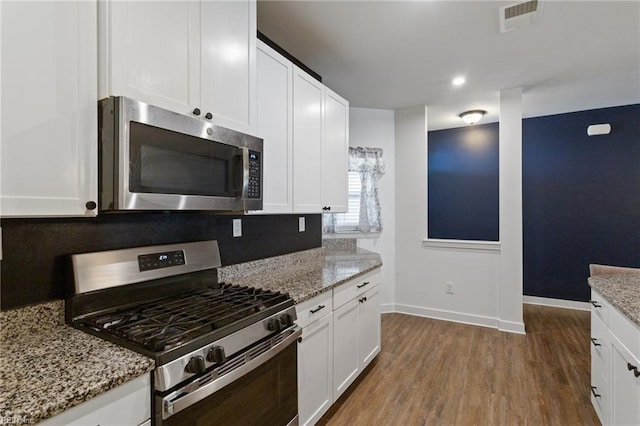 kitchen with white cabinetry, stainless steel appliances, and wood-type flooring