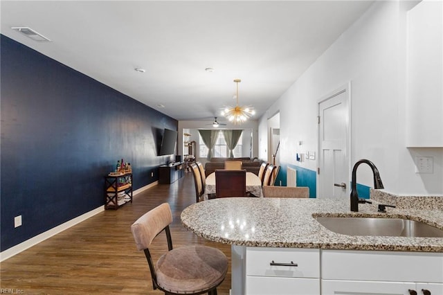 kitchen with white cabinets, dark hardwood / wood-style floors, light stone countertops, and sink