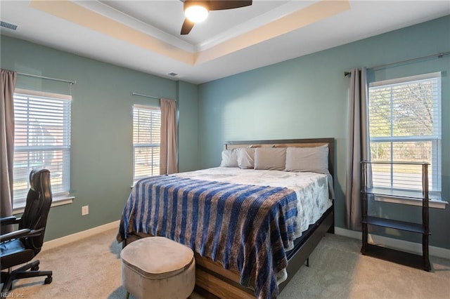 carpeted bedroom featuring ceiling fan, a tray ceiling, and multiple windows