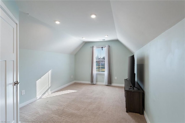 additional living space featuring light colored carpet and vaulted ceiling