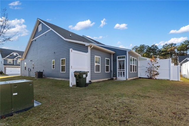 rear view of house with central AC and a yard